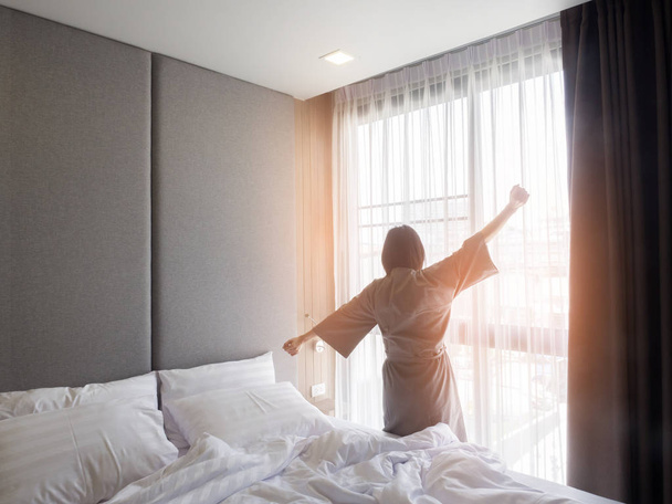 Woman stretching in bed after waking up, back view - Fotoğraf, Görsel