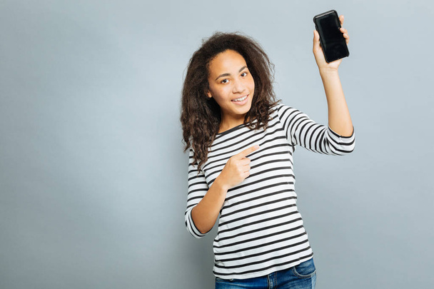 Modern girl pointing at her phone - Zdjęcie, obraz