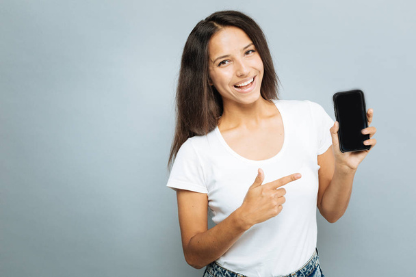 Delighted young woman pointing at her mobile phone - Foto, Imagem