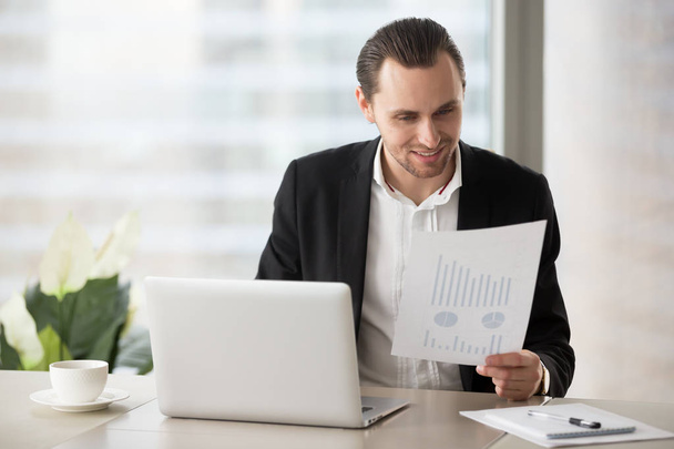 Happy smiling businessman in office looking at financial report - Fotó, kép