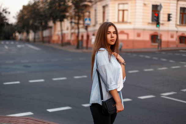 Piękna młoda dziewczyna w stylu casual w niebieską koszulę z torebki w mieście, w pobliżu drogi - Zdjęcie, obraz