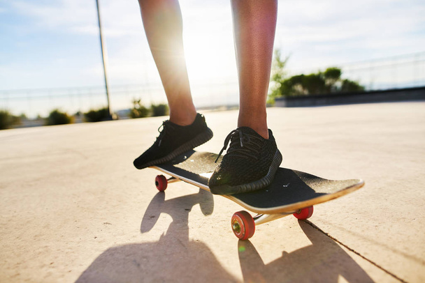 Low section of woman skateboarding on footpath - Фото, изображение