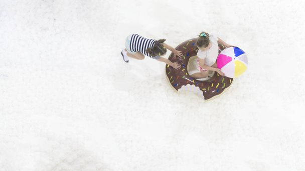 dziewczyny grają i biegać z zabawki balon na białym boisku Bubble na górze widok z lotu ptaka. - Zdjęcie, obraz