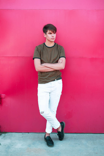 handsome fashionable young man in trendy stylish clothes near a pink metal wall - Fotoğraf, Görsel