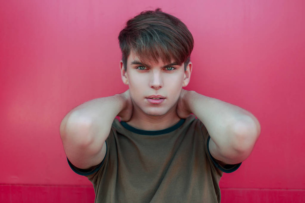 Young stylish man with a haircut in a tank top near a pink metal wall - Фото, зображення