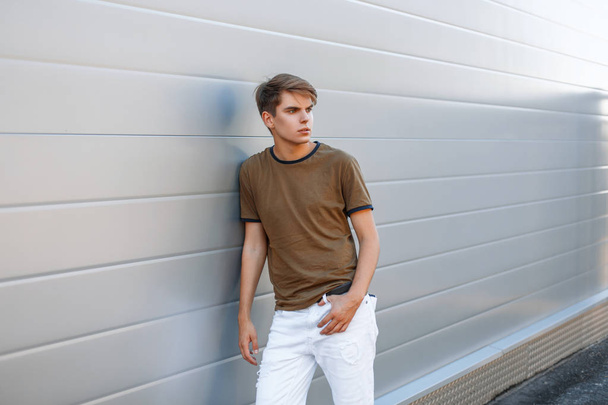 Piękny modny młody człowiek w shirt classic lato w pobliżu błyszczące metalowe ściany - Zdjęcie, obraz