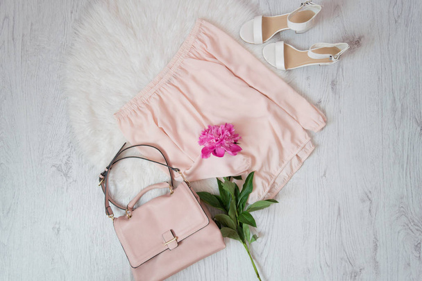 Blusa rosa, bolso, zapatos y un ramo de peonías. Concepto de moda, piel blanca en el fondo
 - Foto, imagen