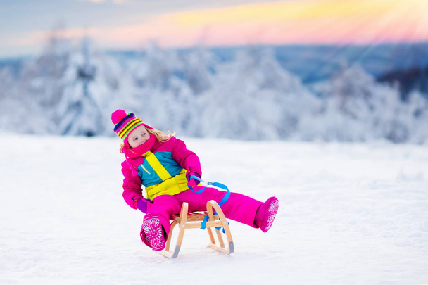 Niño jugando en la nieve en trineo en el parque de invierno
 - Foto, imagen
