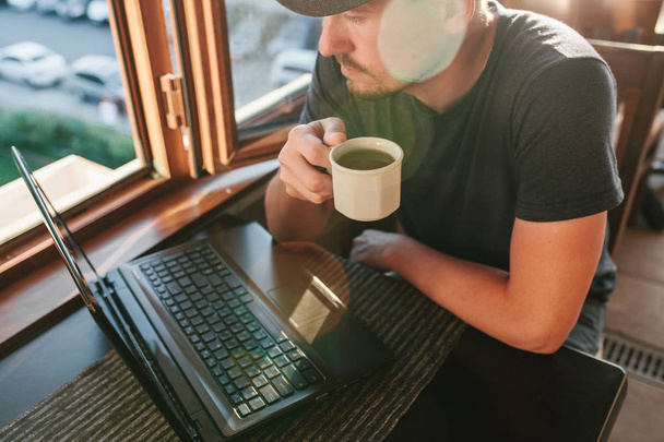 Jeune blogueur touristique masculin pigiste travaillant sur ordinateur portable
. - Photo, image