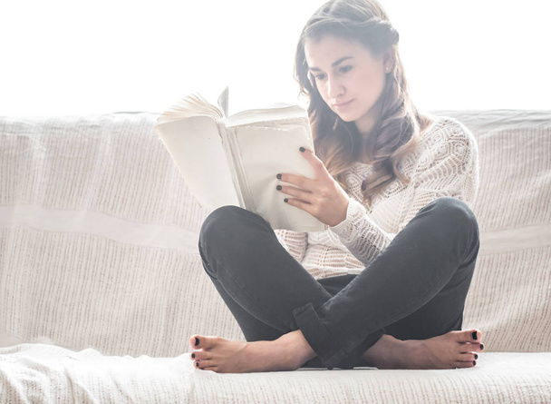 дівчина читає книгу на дивані
 - Фото, зображення