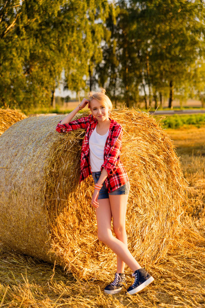 Chica joven en gavillas de paja en un campo
 - Foto, imagen