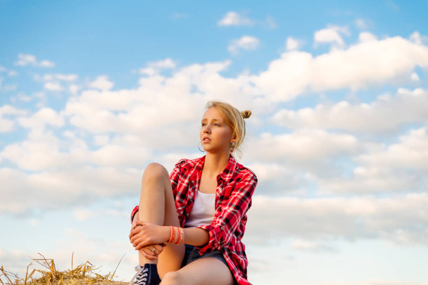 junges Mädchen auf Strohgarben auf einem Feld - Foto, Bild