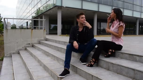 fiatal férfi és fiatal nő ül a lépcsőn, és a füst cigaretta - Felvétel, videó