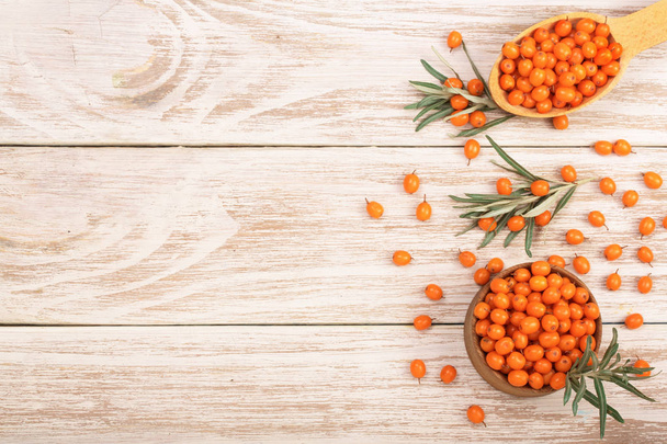 Sea buckthorn. Ripe fresh berries in bowl on white wooden background with copy space for your text. Top view - Foto, afbeelding