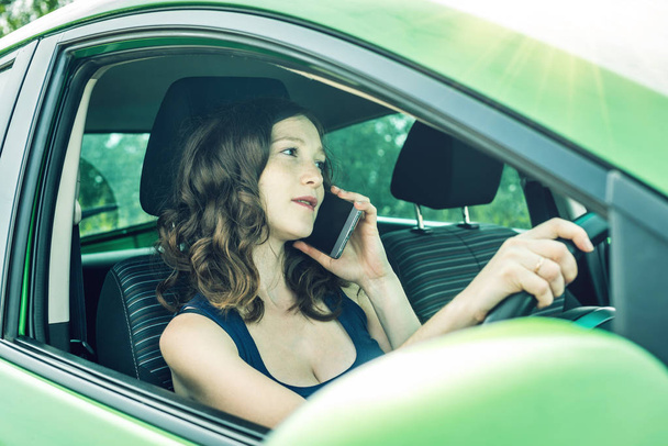 Nő vezető beszél a telefont az autóban. Zavart és veszélyes vezetést. A forgalom megsértése. - Fotó, kép