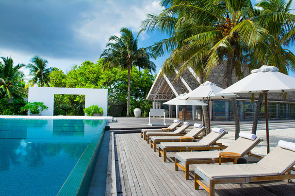 Grande piscina a sfioro sulle rive dell'Oceano Indiano con lettini e ombrelloni all'ombra delle palme
 - Foto, immagini