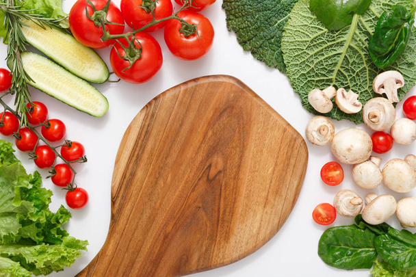 Planche à découper en bois marron, bordure de légumes frais sur fond blanc avec espace de copie
 - Photo, image