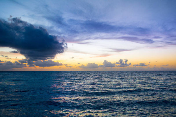 カラフルな空と劇的な波状海雲モルディブ島の砂浜のビーチに美しい日没の風景 - 写真・画像