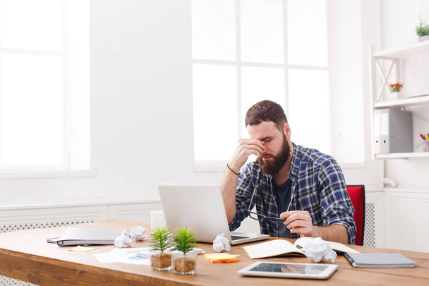 Tired, overworking businessman with laptop in modern white office - Zdjęcie, obraz