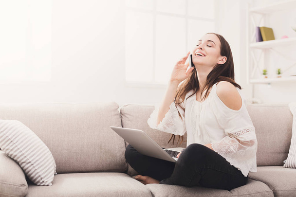 Young laughing woman at home with laptop and mobile - Photo, image
