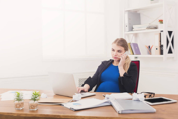 Беременная деловая леди на работе разговаривает по телефону
 - Фото, изображение
