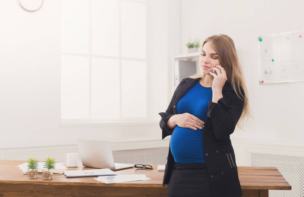 Femme d'affaires enceinte parlant au téléphone au bureau
 - Photo, image