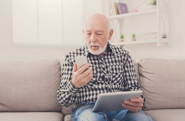 Senior man using phone and tablet - Photo, Image