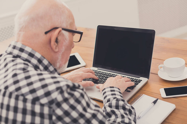 Senior man using laptop with blank screen mockup - Foto, Bild