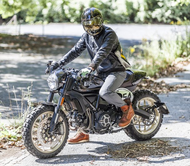 Motorcycle rider on custom made scrambler style cafe racer in th - Photo, Image