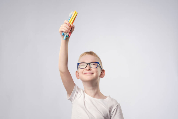 Caucasian boy with blond hair holding pencils in hands and looking up - Photo, Image