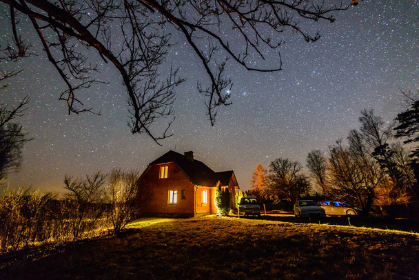 De Melkweg in de nachtelijke hemel met sterren over houten landhuis  - Foto, afbeelding
