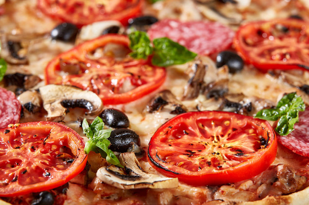 Closeup of pizza with salami, tomatoes and olives - Fotoğraf, Görsel