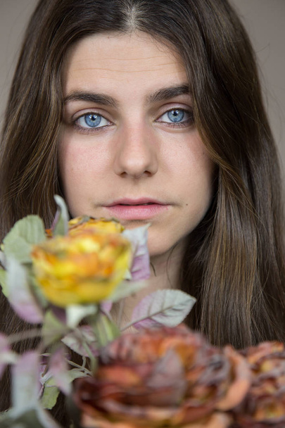 Portret piękna, młoda dziewczyna białe, niebieskie oczy i brązowe włosy trzymając bukiet z suszonych kwiatów. Ona ma poważne spojrzenie i trochę smutny.  - Zdjęcie, obraz