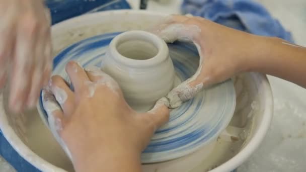 On girder circle teacher helps student to make a pitcher of clay. - Footage, Video