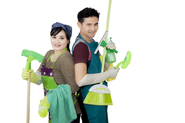 Young couple holding cleaning supplies on studio - Foto, Imagem
