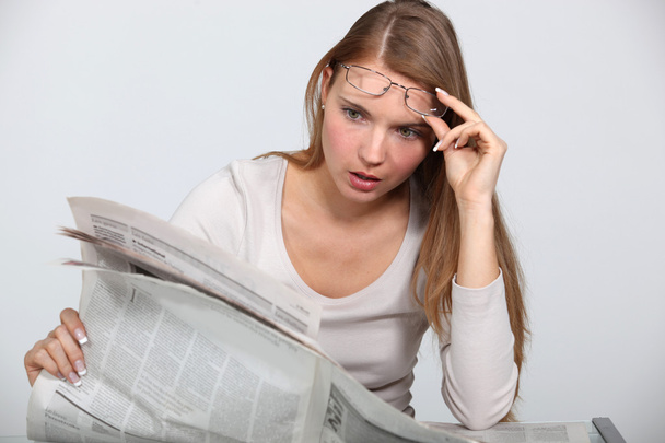 Woman shocked by newspaper article - Фото, изображение