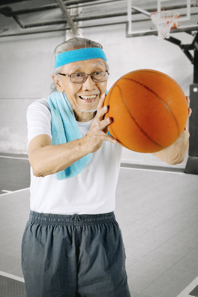 Elderly man playing a basketball in the stadium - Фото, зображення