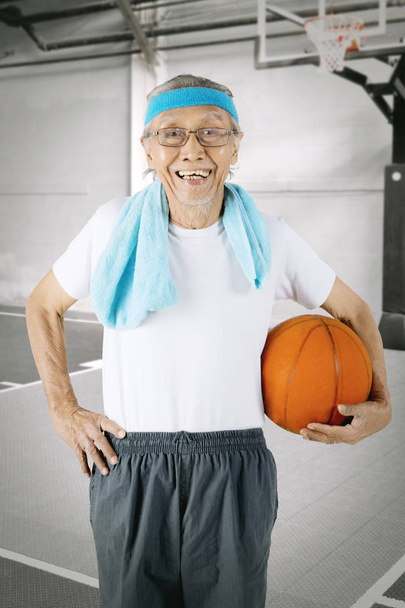 Elderly man carrying a basketball - Фото, зображення