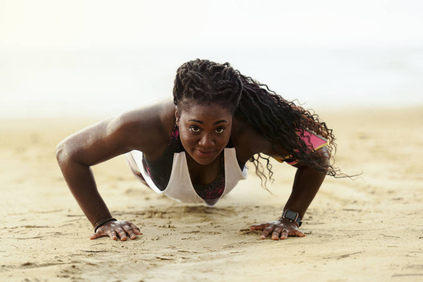 Αφρικανική γυναίκα καταλληλότητας push-ups pushups έξω στην παραλία να κάνει. - Φωτογραφία, εικόνα