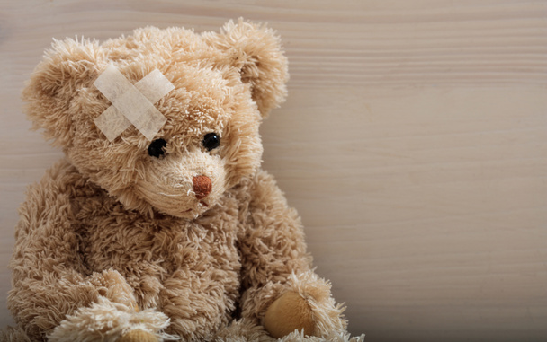 Teddybär mit Binde auf Holzboden - Foto, Bild
