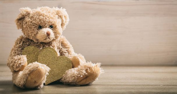 Teddy bear holdimg cuori su un pavimento di legno
 - Foto, immagini