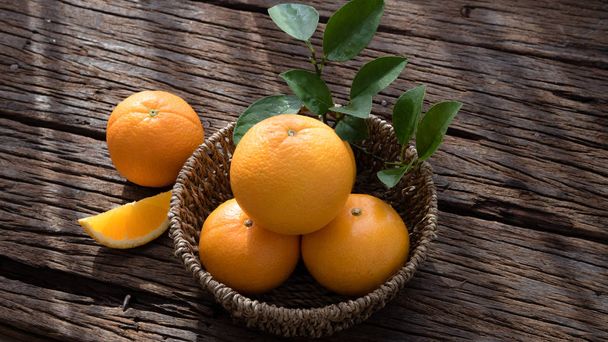 Cesta de fruta naranja puesta en mesa de madera
. - Foto, imagen