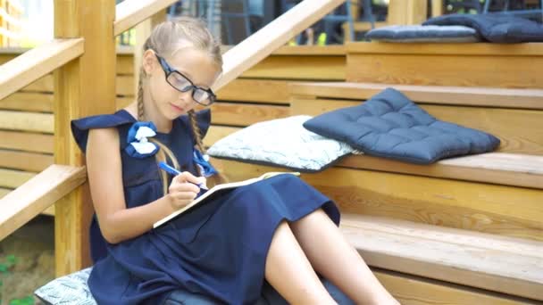 Schattige kleine school meisje met notities en potloden buiten. Terug naar school. - Video