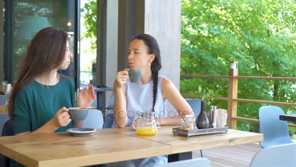 カフェでコーヒーカップを持つ幸せな笑顔の若い女性。コミュニケーションと友情の概念 - 映像、動画