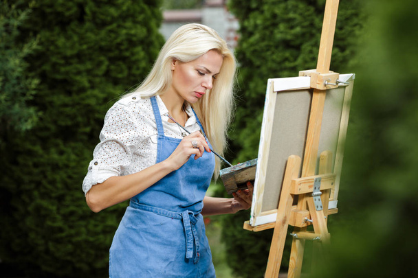 woman artist with a brush in her hand draws on canvas - Fotografie, Obrázek