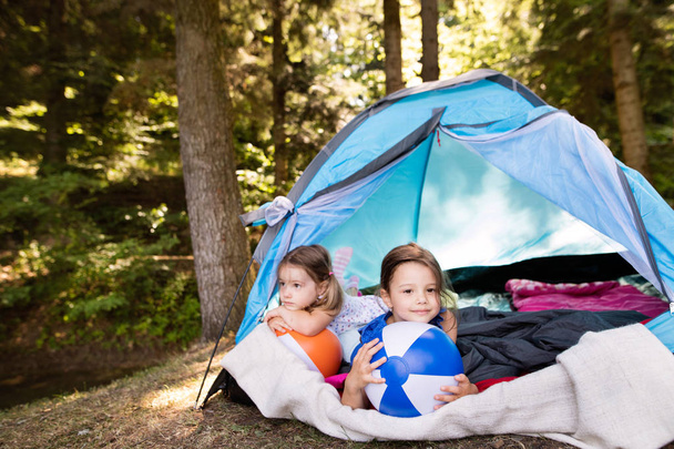 Beautiful little girls in tent camping in the forest. - Фото, зображення