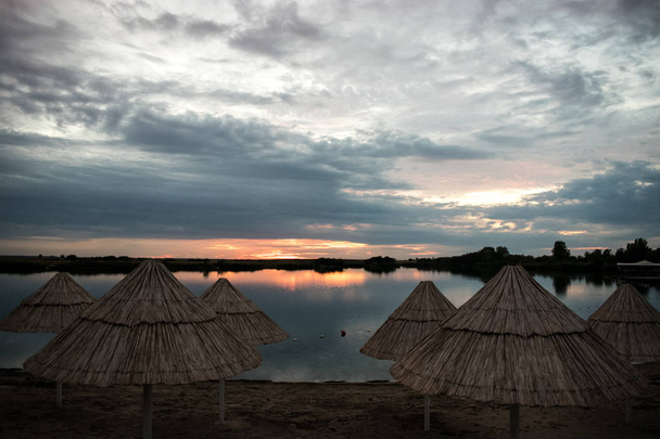 auringonlasku hehku, päivänvarjot kauniilla hiekkarannalla
 - Valokuva, kuva
