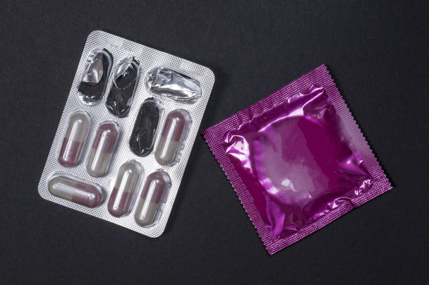 出産の丸薬と黒い背景にコンドーム。避妊の概念 - 写真・画像