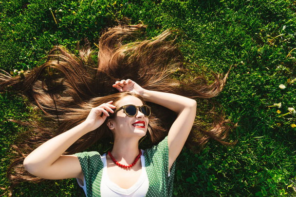 Young girl in glasses,sunglasses,on grass,view above,top.Healthy smile - Fotografie, Obrázek