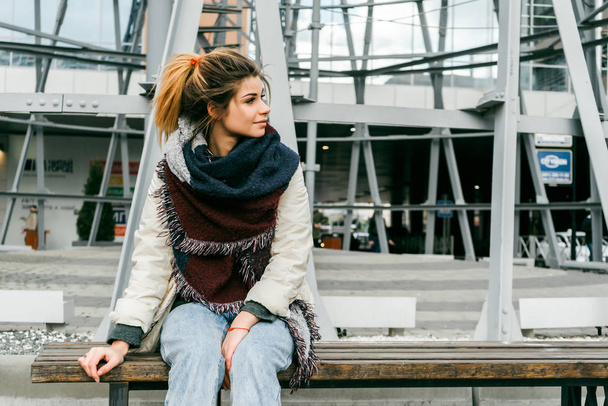 Young beautiful woman sits on a bench in the city - Foto, Bild